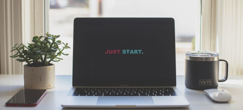 Mc Book on a white table with the typo "Just start"