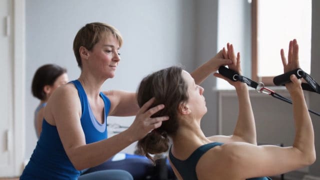 Woman teaches Pilates with the Reformer