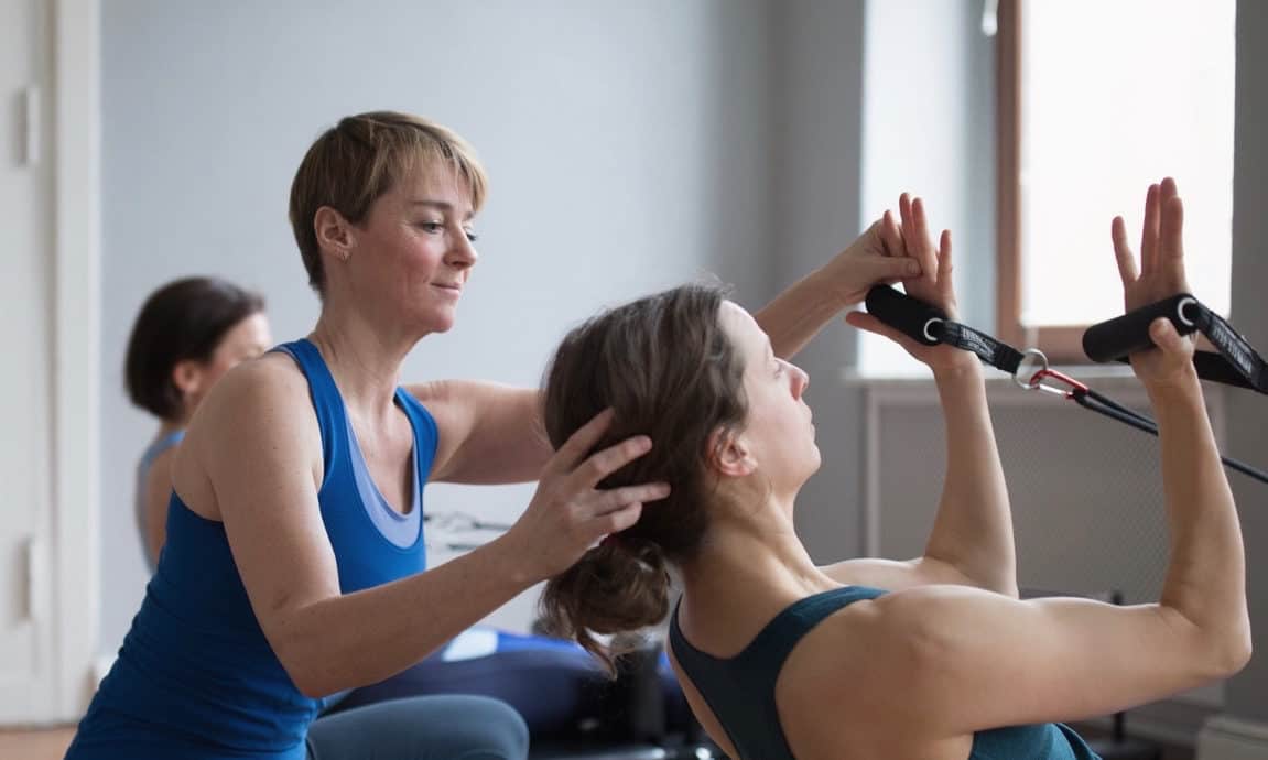 Woman teaches Pilates with the Reformer
