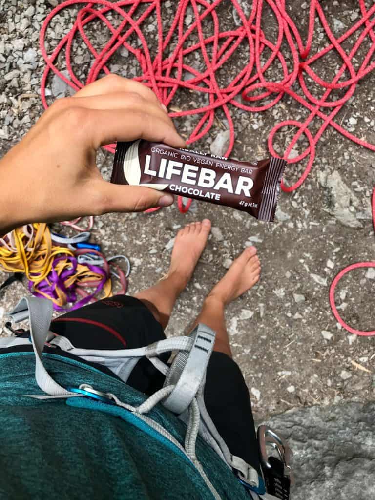 praticante de escalada com barra de proteína lifebar na mão