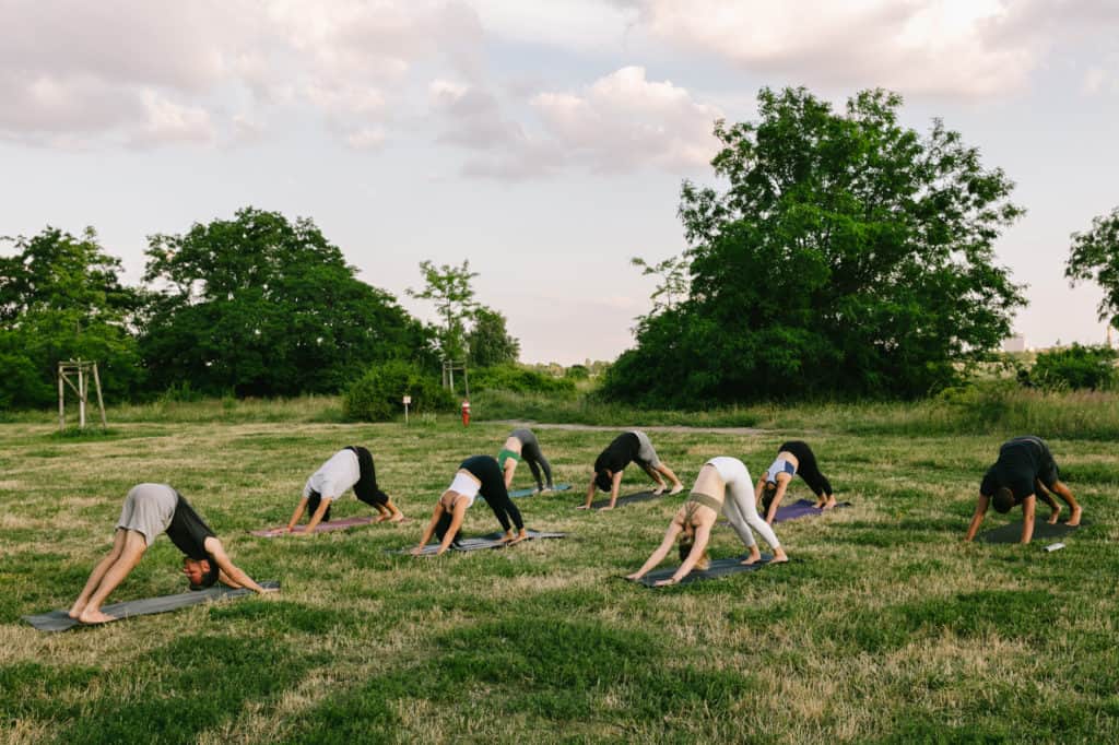 grupo de pessoas a treinar ao ar livre enquanto praticam yoga no parque