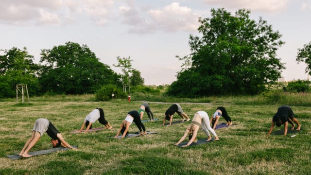 grupo de pessoas a treinar ao ar livre enquanto praticam yoga no parque