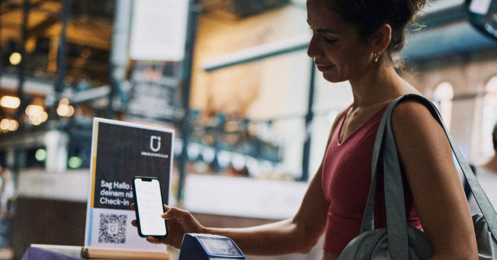 Frau checkt mit der Urban Sports Club App ins Fitnessstudio ein
